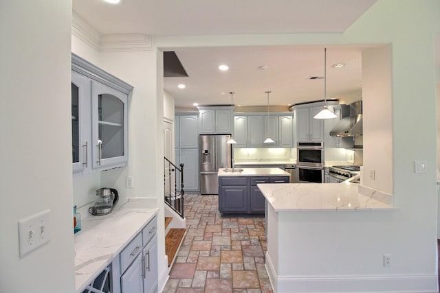 kitchen featuring wall chimney range hood, recessed lighting, gray cabinets, appliances with stainless steel finishes, and stone tile flooring