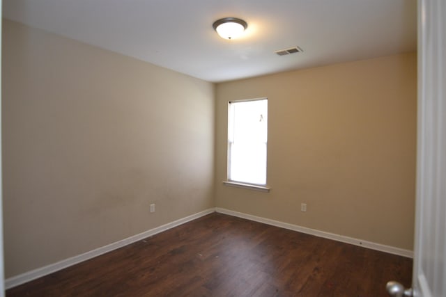 empty room with dark wood-type flooring, baseboards, and visible vents