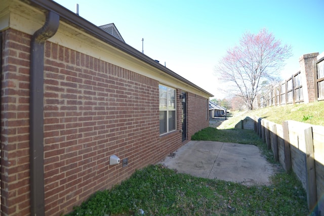 view of home's exterior featuring brick siding, a patio area, and fence