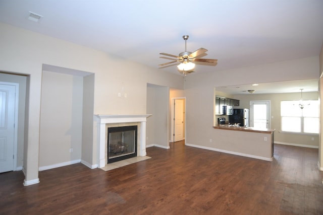 unfurnished living room with baseboards, a ceiling fan, dark wood-style flooring, and a tile fireplace