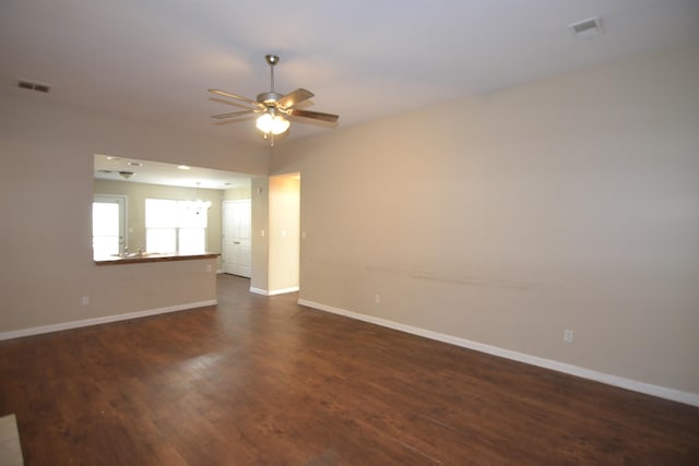 unfurnished room with dark wood finished floors, ceiling fan with notable chandelier, baseboards, and visible vents