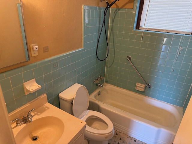 full bathroom with a wainscoted wall, toilet, shower / washtub combination, tile walls, and vanity