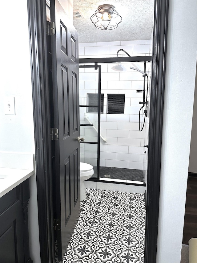 bathroom featuring vanity, visible vents, a shower stall, a textured ceiling, and toilet