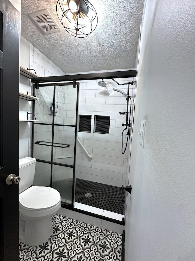 bathroom with visible vents, a stall shower, toilet, and a textured ceiling