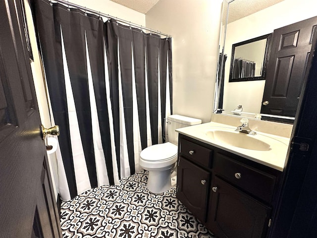 bathroom featuring vanity, toilet, tile patterned flooring, and a textured ceiling