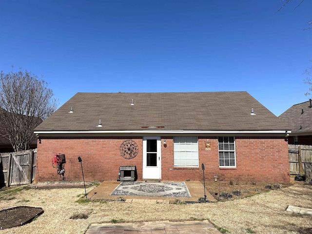 rear view of property with brick siding, a patio area, and fence