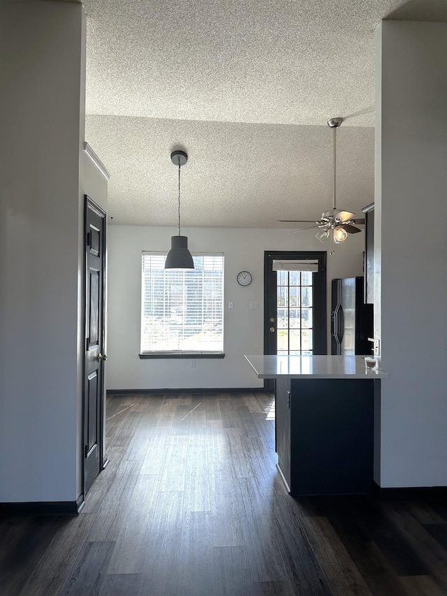 kitchen with fridge with ice dispenser, a textured ceiling, ceiling fan, dark wood-style flooring, and hanging light fixtures