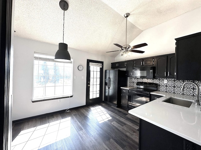 kitchen featuring a sink, light countertops, lofted ceiling, black appliances, and dark cabinets