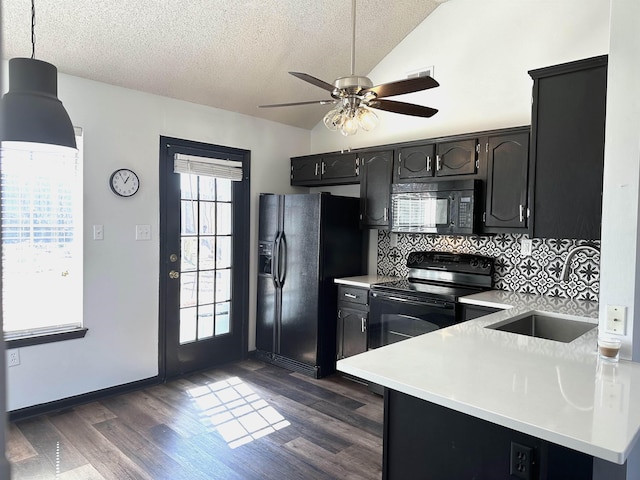 kitchen with a sink, black appliances, dark wood-style floors, and vaulted ceiling