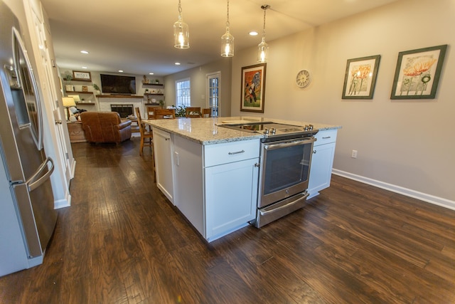 kitchen featuring light stone countertops, dark wood finished floors, a fireplace, appliances with stainless steel finishes, and white cabinetry