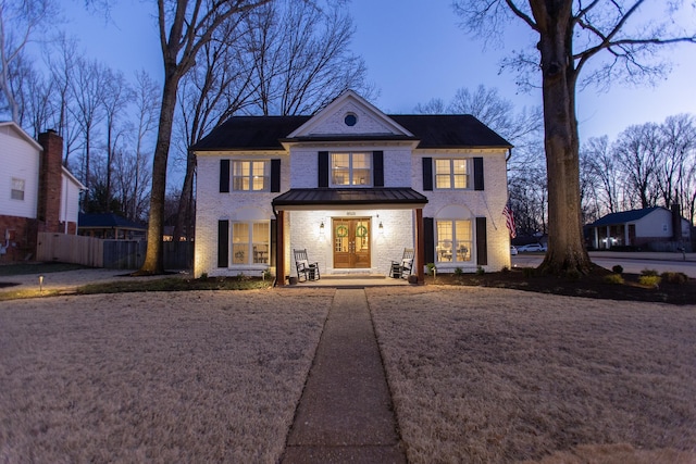 view of front facade featuring fence, french doors, and brick siding