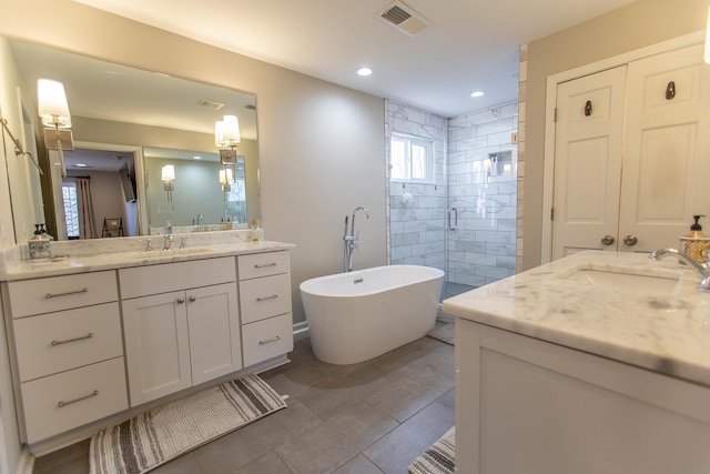 full bathroom with a stall shower, visible vents, a freestanding tub, and a sink