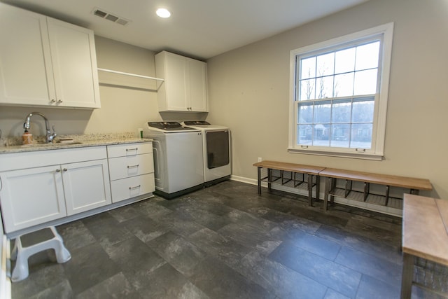 clothes washing area with visible vents, baseboards, washer and dryer, cabinet space, and a sink