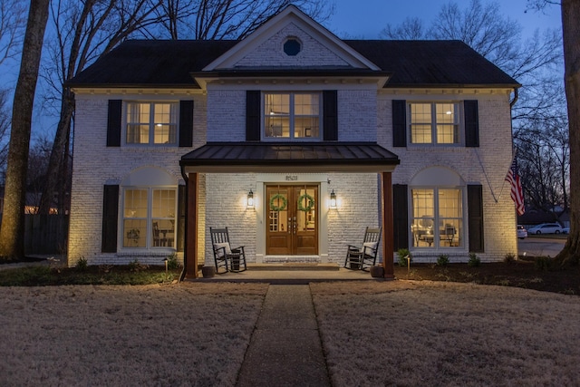 view of front of property featuring french doors, brick siding, metal roof, and a standing seam roof