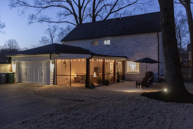 rear view of house with a patio, brick siding, and fence