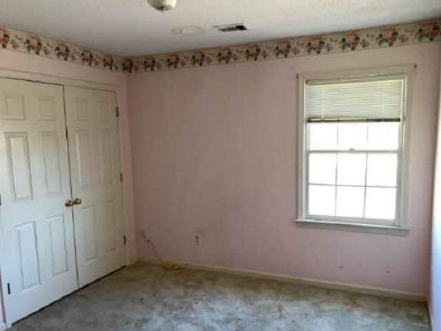 unfurnished bedroom with a closet, baseboards, carpet, and visible vents