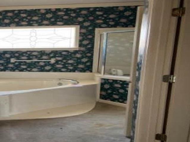 bathroom featuring wallpapered walls and a bath