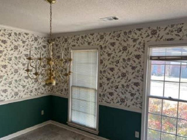 spare room featuring visible vents, a textured ceiling, wainscoting, and wallpapered walls