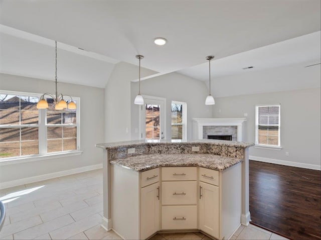 kitchen with light stone counters, lofted ceiling, pendant lighting, and a fireplace