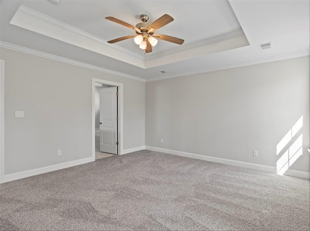 carpeted spare room featuring visible vents, baseboards, crown molding, and a tray ceiling