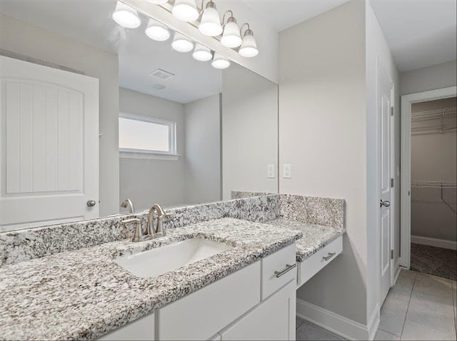 bathroom with vanity, baseboards, visible vents, tile patterned flooring, and a spacious closet