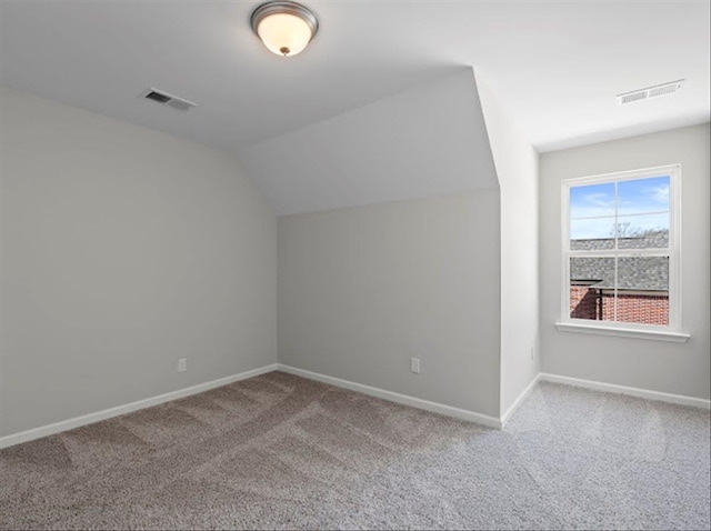 additional living space with visible vents, carpet flooring, baseboards, and vaulted ceiling