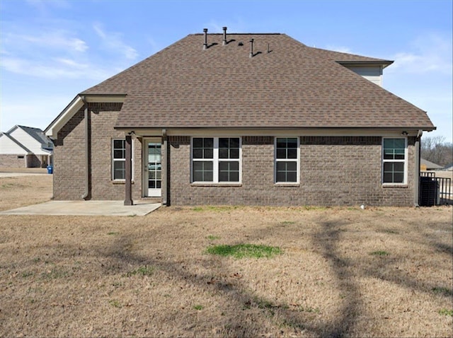 back of property featuring brick siding, a lawn, a shingled roof, and a patio