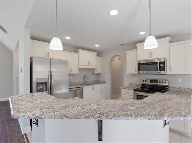 kitchen featuring recessed lighting, appliances with stainless steel finishes, arched walkways, white cabinets, and a sink