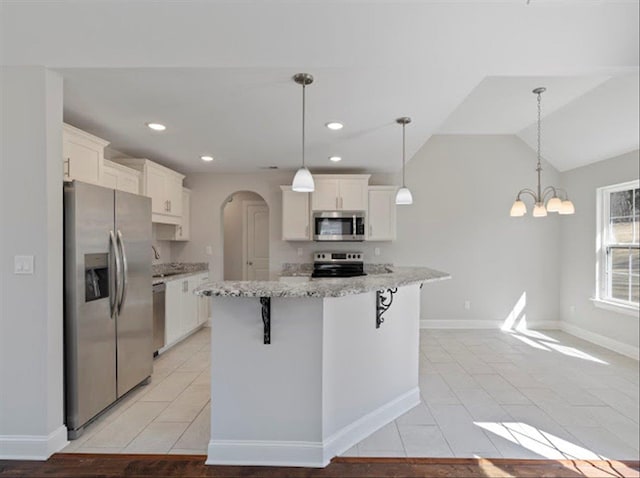 kitchen featuring arched walkways, white cabinets, appliances with stainless steel finishes, and vaulted ceiling