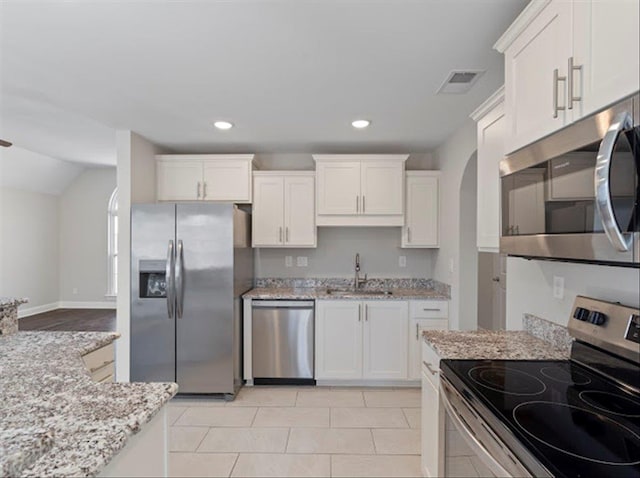 kitchen featuring visible vents, light stone counters, appliances with stainless steel finishes, white cabinets, and a sink