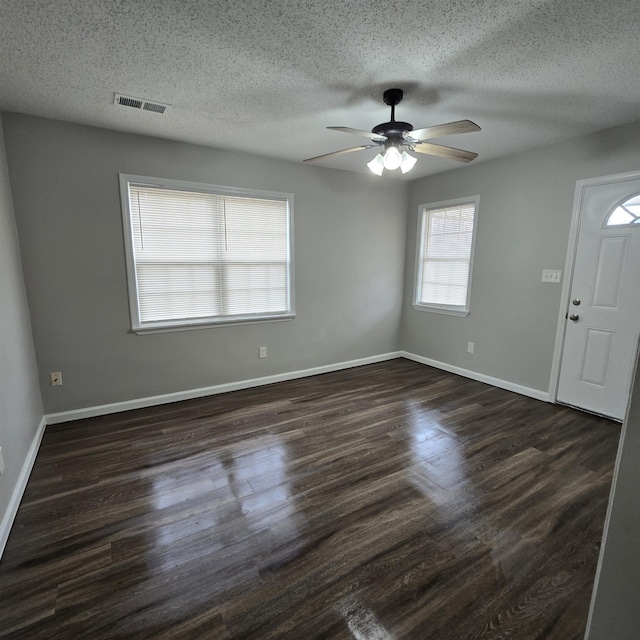 interior space featuring visible vents, baseboards, dark wood finished floors, and a ceiling fan