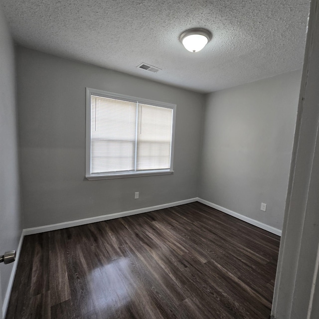 unfurnished room with dark wood-style floors, visible vents, a textured ceiling, and baseboards