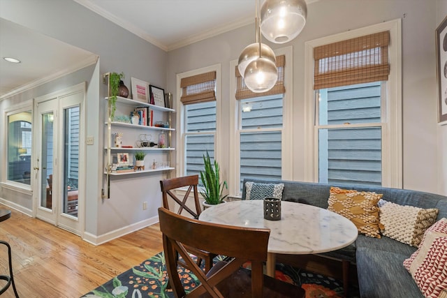 dining area with breakfast area, light wood-type flooring, baseboards, and crown molding