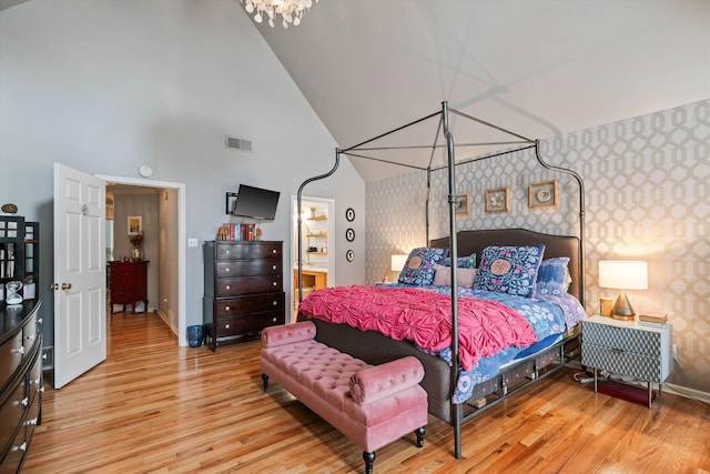 bedroom with baseboards, visible vents, wallpapered walls, an accent wall, and light wood-type flooring