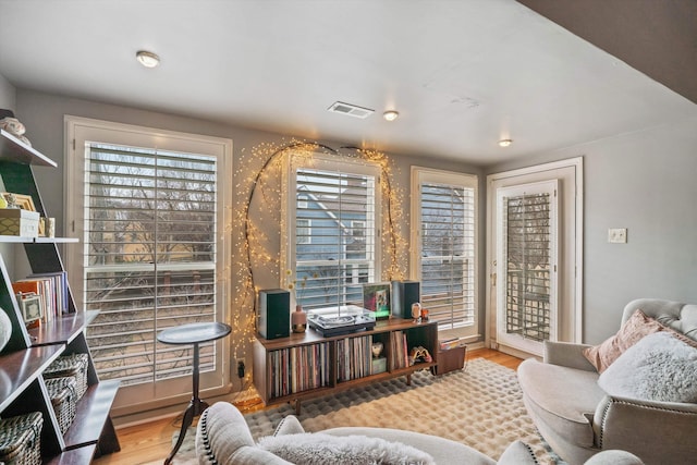 living area featuring visible vents and wood finished floors