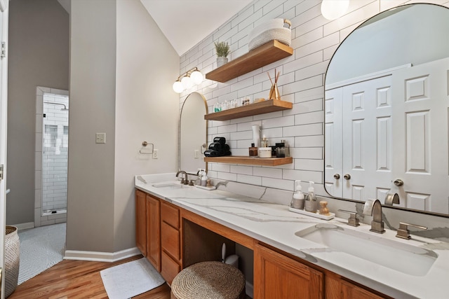 full bath featuring a sink, decorative backsplash, wood finished floors, and double vanity