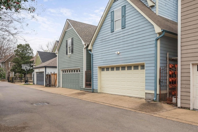 view of property exterior with an attached garage and a shingled roof