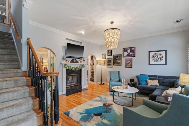 living room featuring visible vents, a tiled fireplace, wood finished floors, stairway, and arched walkways