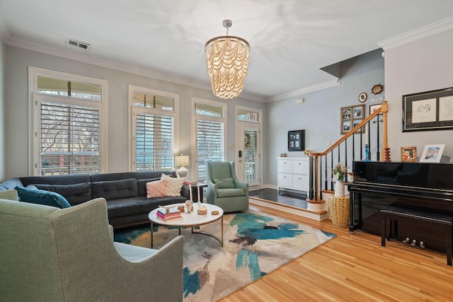 living area with stairs, wood finished floors, visible vents, and ornamental molding