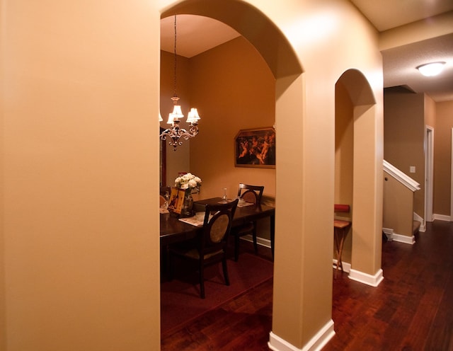 corridor featuring stairway, an inviting chandelier, baseboards, and wood finished floors