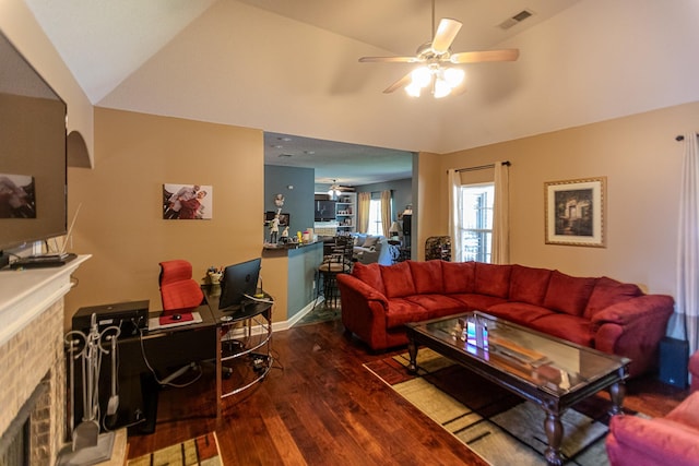 living area featuring visible vents, ceiling fan, vaulted ceiling, a fireplace, and wood finished floors