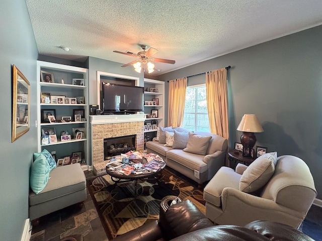 living room with a textured ceiling, built in features, a ceiling fan, stone finish flooring, and a brick fireplace