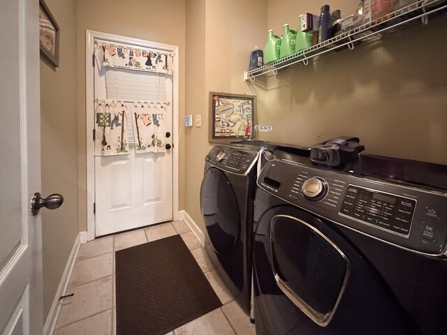 washroom with light tile patterned floors, baseboards, laundry area, and washing machine and clothes dryer