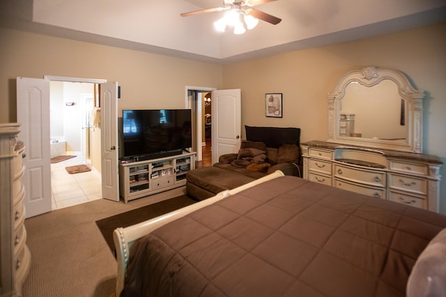 bedroom featuring a tray ceiling, connected bathroom, ceiling fan, and carpet flooring