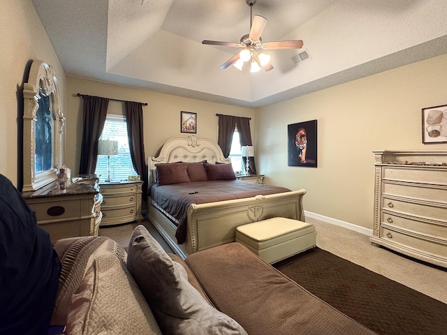 bedroom featuring a tray ceiling, baseboards, visible vents, and carpet flooring