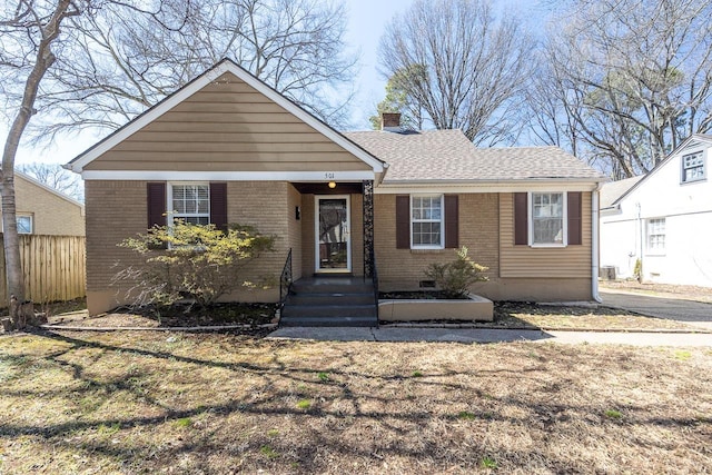 view of front of home featuring fence, brick siding, a chimney, and a shingled roof