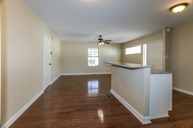 corridor featuring visible vents, dark wood-type flooring, and baseboards