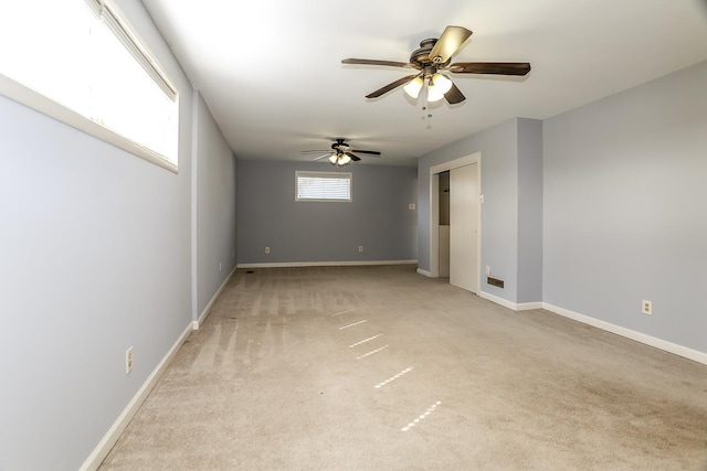 empty room with light carpet, a ceiling fan, and baseboards