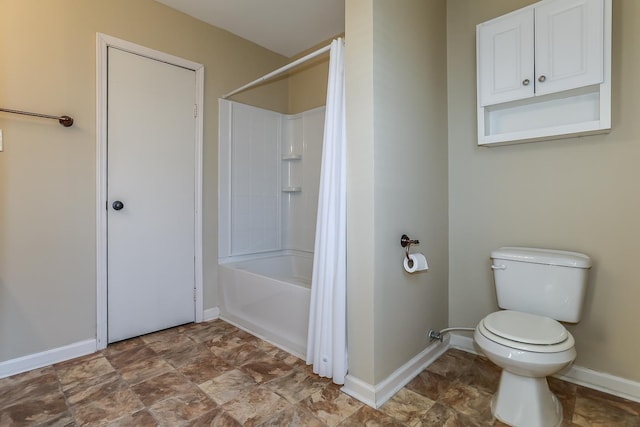 full bath featuring shower / bath combo with shower curtain, toilet, stone finish flooring, and baseboards