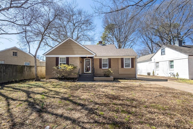 view of front of home with brick siding, a chimney, and fence